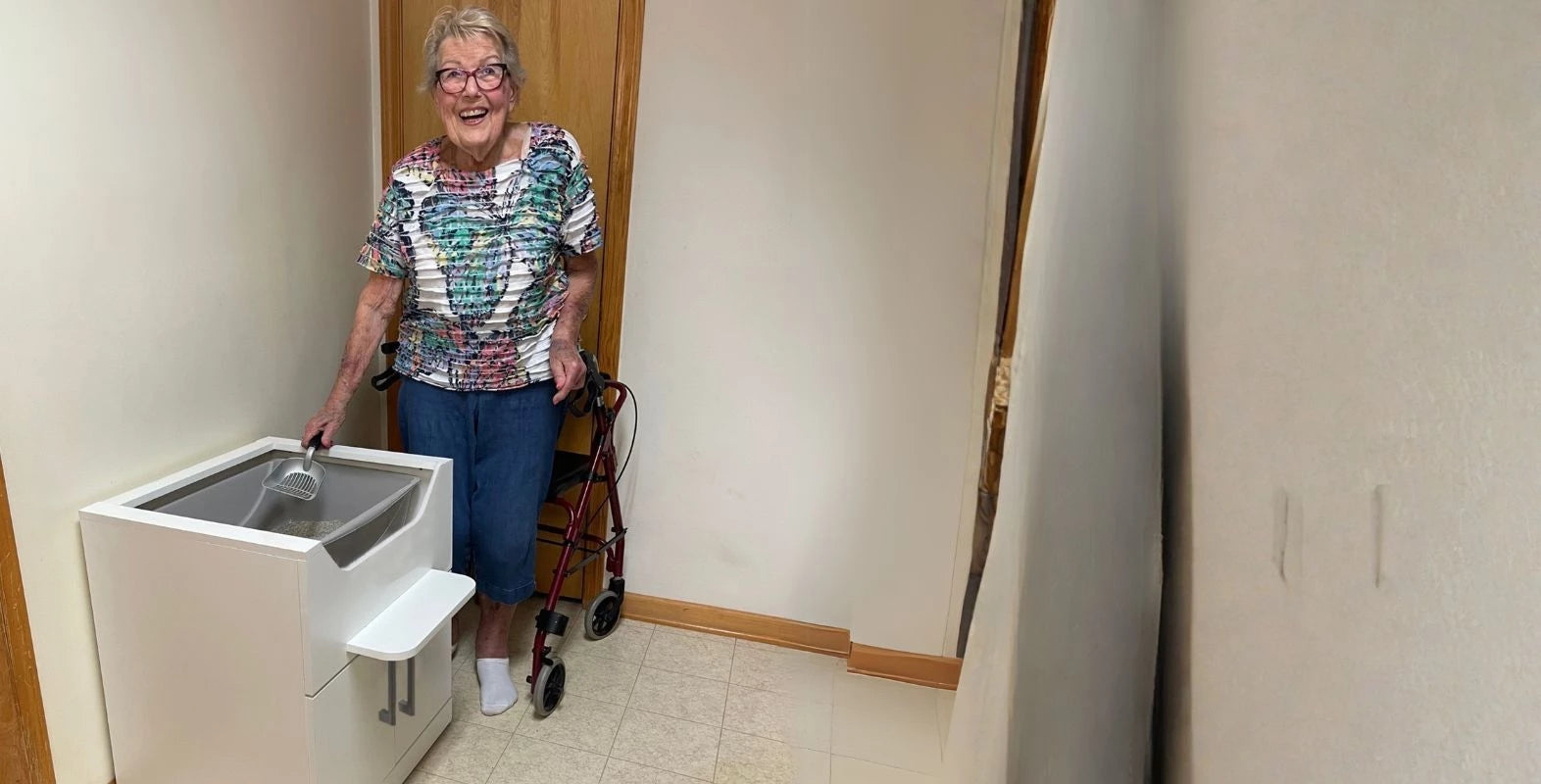 Elderly woman standing to scoop an elevated cat litter box