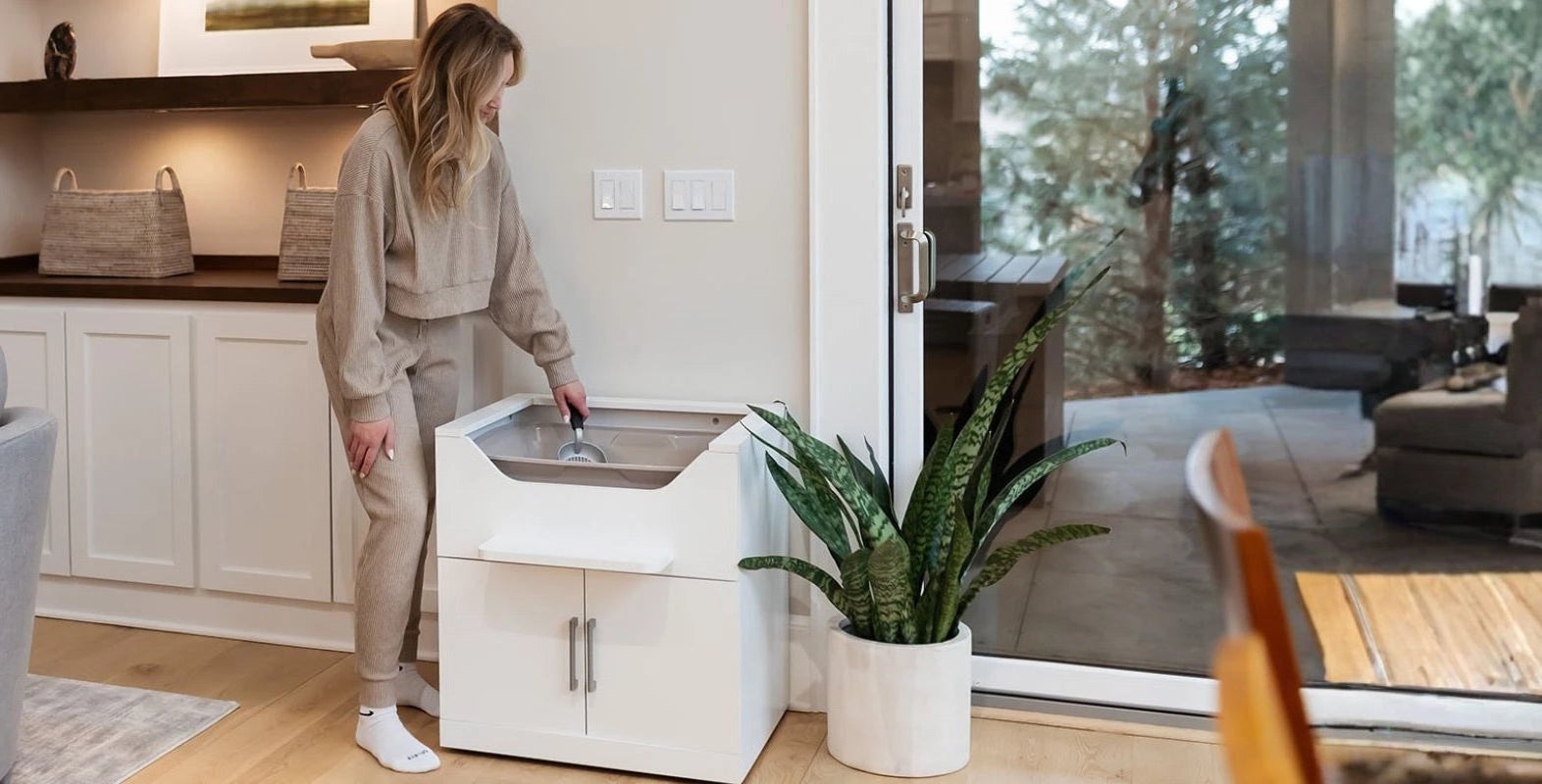 Woman standing to scoop a luxury elevated cat litter box by LoftyLoo