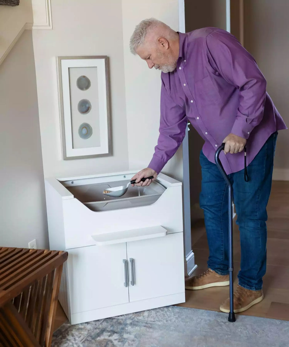 Raised litter box cleaned by man using a cane 