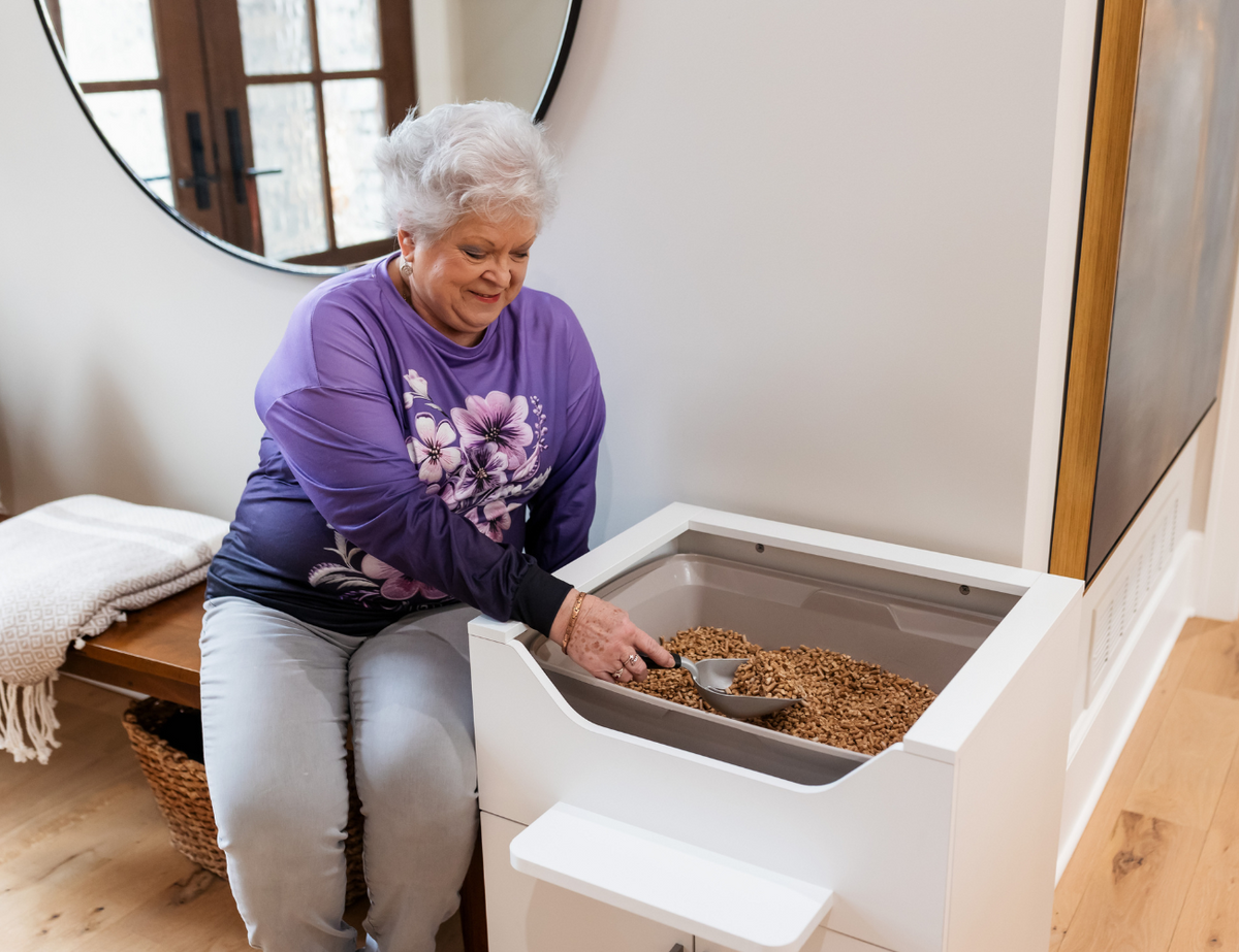 A senior woman sitting while scooping a LoftyLoo easy-to-clean litter box
